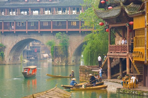 Fenghuang, China, September 10, 2007: Tourists and boats hang around riverside at the Phoenix Hong