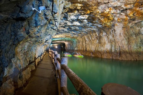 A pair of blurred tourist boats navigate the old flooded military installation, the Beihei Tunnel,