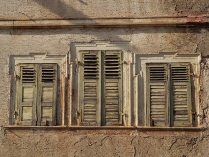 Three old windows with weathered green shutters on a ruined house wall, Kandel, Palatinate,