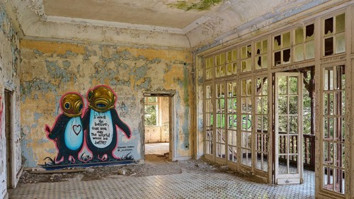 Abandoned room with graffiti on the wall, tiled floor and nature view through the windows,