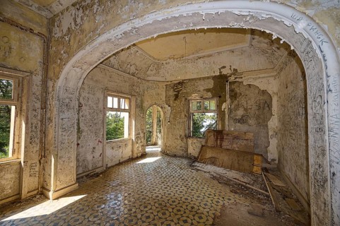 Dilapidated room with arched architecture, dilapidated walls and flooded with bright natural light,