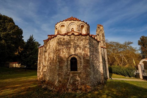 Old stone church with a simple design, in a wooded setting under a blue sky, Byzantine chapel of