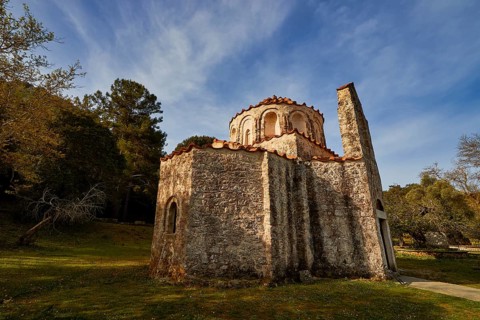 Historic church with stone façade in a rural landscape under a blue sky, Byzantine chapel Agios