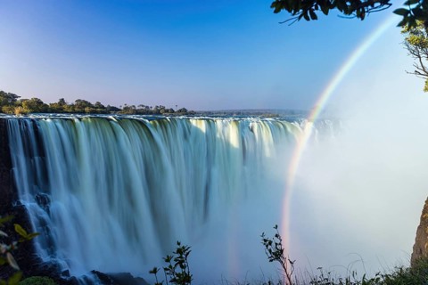 Scenic view of rainbow arching the Zambezi river waterfall of Victoria Falls in Zimbabwe