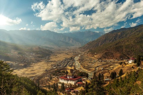 Sunrays through the clouds as the sun is setting over Paro