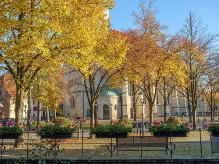 Church in autumn with yellow glowing trees and flower beds in the foreground, nottuln, münsterland,