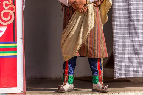 Spectator in traditional colorful clothing at a tshechu festival in Bhutan