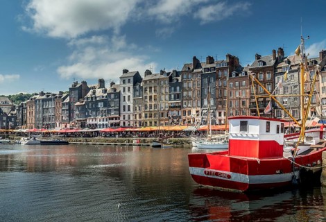 Red boat in front of the pitiresque buildings in Honfleur, Normandy