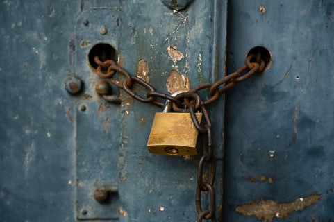 Old weathered door locked with a padlock and a rusty chain