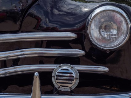 Close-up of a black classic car, showing the front headlight and the chrome grille, winterswijk,