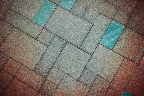 Geometric pattern of pavement tiles in blue and brown tones, creating a textured urban flooring