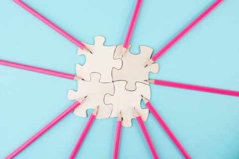 Working as a team, puzzle pieces connect together, pencils point to the jigsaw, brainstorming for