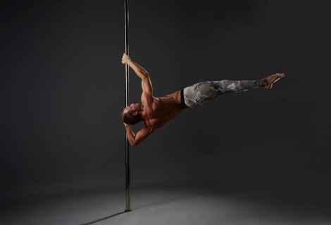 Image of strong gymnast exercising on pylon in studio