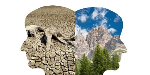 Silhouette of two faces look to the opposite direction, one with green nature, mountains, the other
