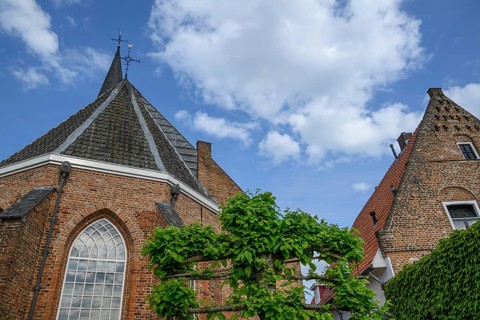 Red brick church with gothic architecture and high towers, someone in a village in good weather,