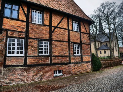 Half-timbered brick house with white windows in an autumnal ambience, church in the background,
