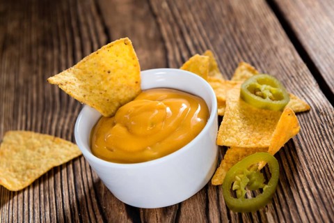 Portion of Nachos (with Cheese Dip) on an old wooden table