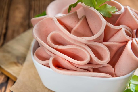 Portion of sliced Mortadella on wooden background (selective focus)
