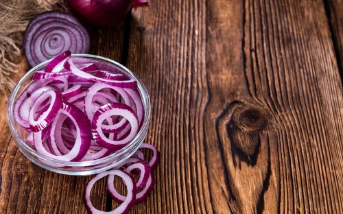 Fresh cutted Red Onion rings (close-up shot) on an old wooden table