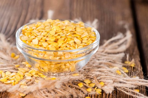 Portion of Yellow Lentils on vintage wooden background