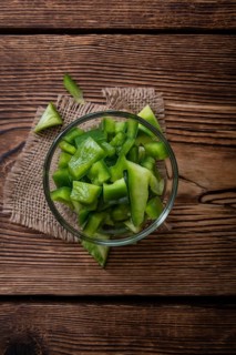 Portion of green Peppers (sliced, selective focus) on wooden background