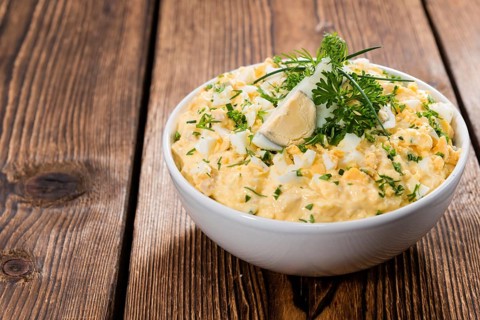 Portion of Egg Salad (fresh homemade with herbs) on wooden background