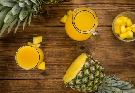 Pineapple Juice as high detailed close-up shot on a vintage wooden table, selective focus