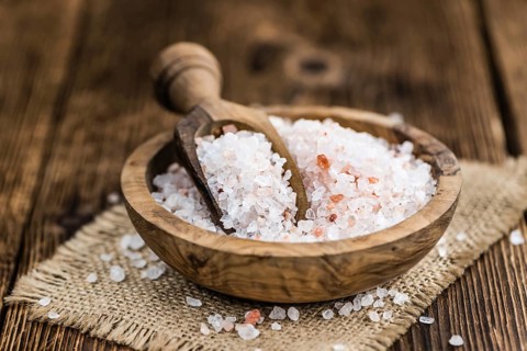 Salt (pink) on an old wooden table as detailed close-up shot (selective focus)