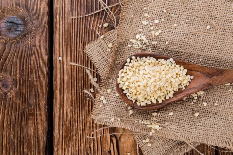 Portion of Minced Almonds (detailed close-up shot) on dark wooden background