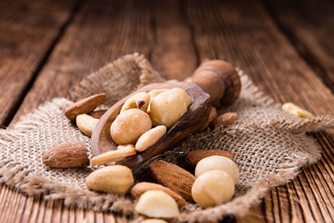 Portion of mixed nuts (roasted and salted) on an old wooden table (selective focus)