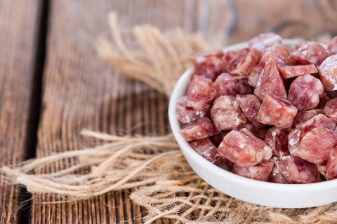 Portion of Mini-Salamis (detailed close-up shot) on wooden background