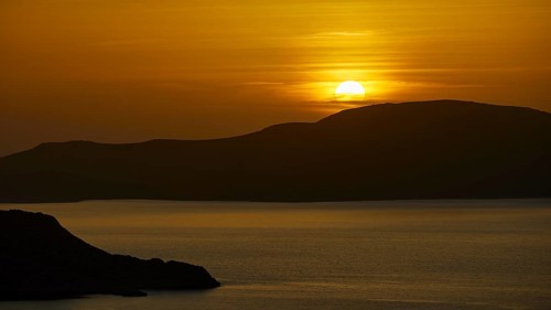 A peaceful seascape at sunset, hills in the background, illuminated by warm golden light, Makri