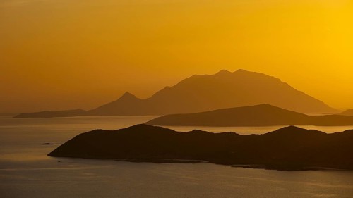 Golden sunset over the sea with silhouetted mountains in the background, Makri Island, Alimia