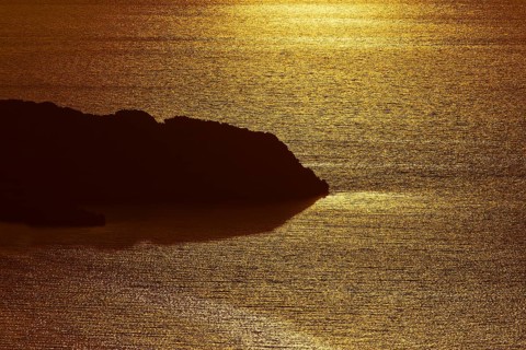 Coastal silhouette in golden light, calm sea reflecting the sunset, Kritinia Castle, St John's