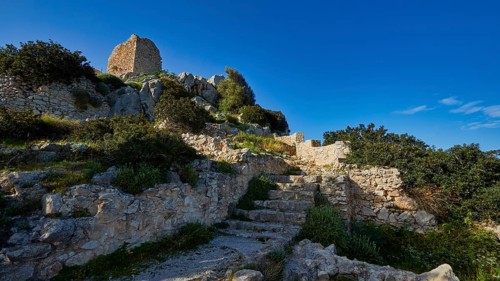 Remains of a castle on a hill with stone steps and vegetation under a clear sky, Kritinia Castle,