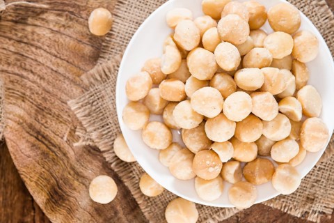Portion of Macadamia nuts (roasted and salted) on wooden background