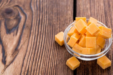 Pieces of Cheddar (close-up shot) on an old wooden table