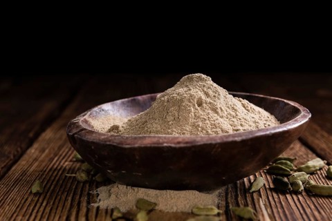 Heap of Cardamon Powder (close-up shot) on rustic wooden background
