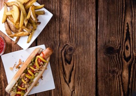 Homemade Hot Dog with fried onions and sauces on rustic wooden background