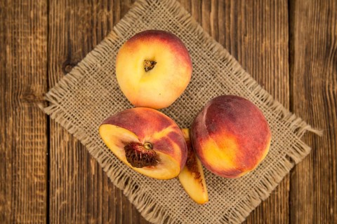 Fresh Peaches as high detailed close-up shot on a vintage wooden table, selective focus