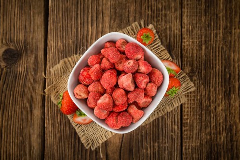 Strawberries (dried) as high detailed close-up shot on a vintage wooden table, selective focus