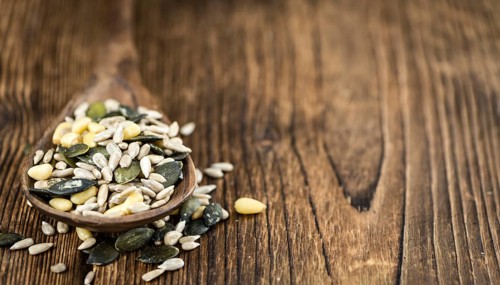 Portion of mixed Seeds (close-up shot, selective focus) on wooden background