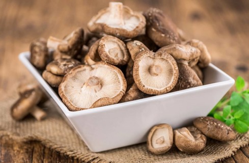 Raw Shiitake mushrooms as high detailed close-up shot on a vintage wooden table, selective focus