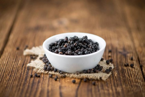 Preserved black Peppercorns on wooden background, selective focus, close-up shot