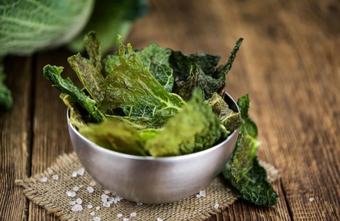 Healthy Savoy Chips on a wooden table as detailed close-up shot (selective focus)
