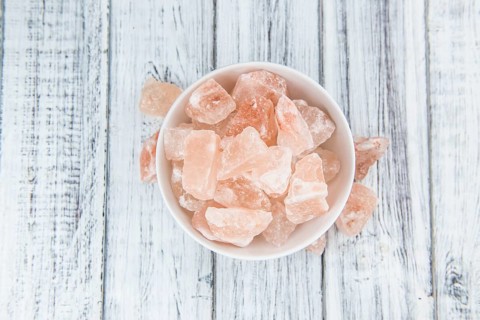 Wooden table with a portion of pink Salt (close-up shot, selective focus)