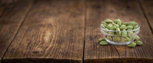 Wasabi coated Peanuts as high detailed close-up shot on a vintage wooden table (selective focus)