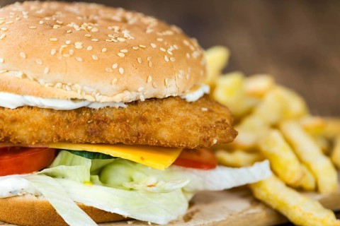 Wooden table with a fresh made Fish Burger (close-up shot, selective focus)