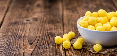 Cheese Balls (fried) as high detailed close-up shot on a vintage wooden table (selective focus)