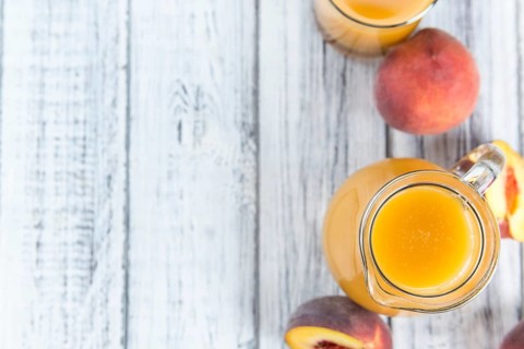 Portion of Peach juice (fresh made) on an old wooden table (close-up shot)